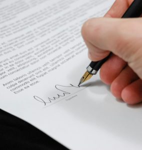 Close-up of a hand signing a legal document with a fountain pen, symbolizing signature and agreement.