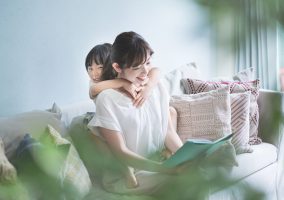 Mother and daughter sitting on the sofa and reading a picture book